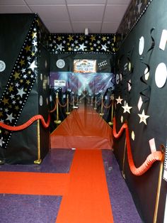 an orange carpeted hallway with black and white decorations on the walls, red rope