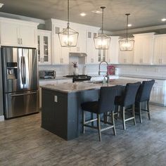 a kitchen with white cabinets and gray counter tops, stainless steel appliances and an island in the middle