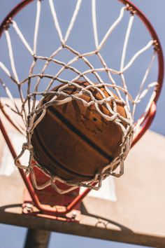 a basketball going through the rim of a hoop with net on it's back