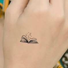 a woman's hand with a book tattoo on it