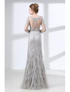 a woman in a long silver dress with an open back and beading on it