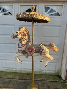 a carousel horse is standing in front of a garage