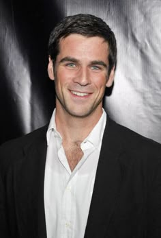 a smiling man in a black suit and white shirt