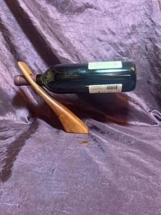 a bottle of wine and a wooden paddle on a purple cloth