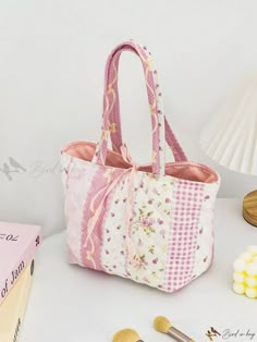 a pink and white bag sitting on top of a table next to some makeup brushes