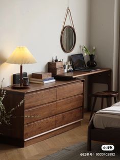 a bedroom scene with focus on the dresser and bed, lamp and laptop sitting on it