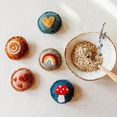 four different types of buttons on a white surface next to a wooden spoon and bowl