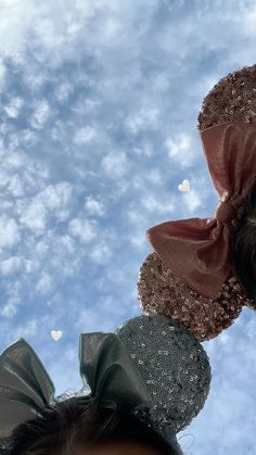 two women with hair bows on their heads looking up at the sky in front of them