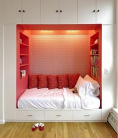 there is a small bed in the corner of this room with red and white walls