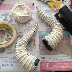 scissors, tape and other crafting supplies on top of a newspaper