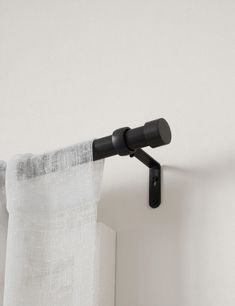 the curtain is hanging on the side of the wall with a black rod attached to it