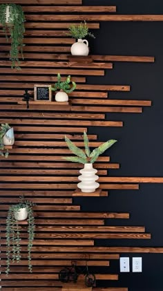 some plants are sitting in white vases on wooden slatted wall behind them