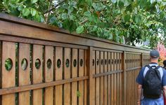 a man with a backpack is walking by a wooden fence