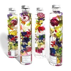 three glass bottles with flowers in them sitting next to each other