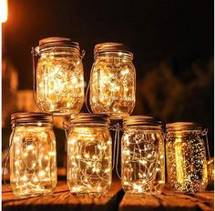 mason jars filled with fairy lights sitting on top of a wooden table