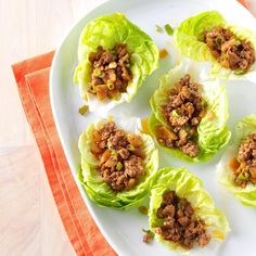 three lettuce wraps filled with meat and veggies on a white plate