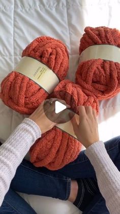 a woman is holding two orange towels on top of her feet while sitting on a bed