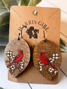 the earrings are made out of wood and have red birds on them, with white flowers