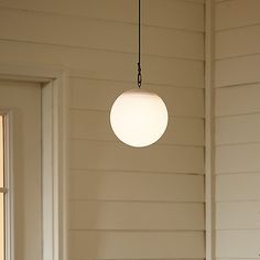 a white light hanging from a ceiling in a living room next to a door and window