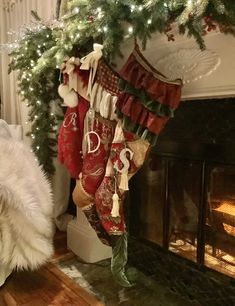 a white dog sitting in front of a fireplace with stockings hanging from it's mantle