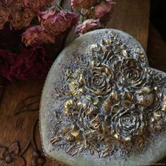 a heart shaped rock with flowers in the middle on a wooden table next to it