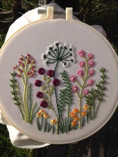 a close up of a embroidery on a piece of cloth with flowers in the background