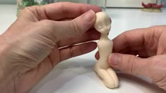 two hands are working on a small figurine