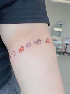 a woman's arm with small tattoos on the left side of her body, including cats and hearts