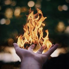 a person holding their hands in the air with fire coming out of it's center