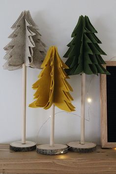 three wooden trees are on top of a shelf next to a chalkboard and some lights