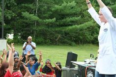 a man standing in front of a group of people holding their hands up to the sky