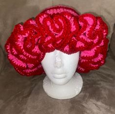 a white mannequin head wearing a red crocheted hat with roses on it