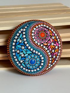 a colorful painted rock sitting on top of wooden planks next to a white surface