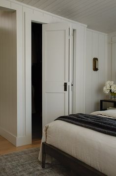 a bed sitting in a bedroom next to a white closet with doors on both sides