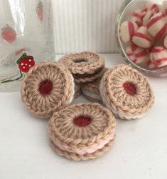 small crocheted cookies sitting on top of a table next to a bowl of candy