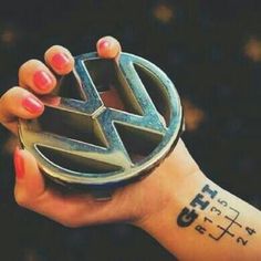 a woman's arm with a small tattoo on it and a car symbol tattooed on the wrist