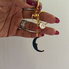 a woman's hand holding onto a gold and blue crescent shaped keychain