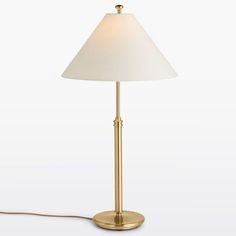 a gold lamp with a white shade on it and a cord plugged into the base