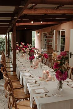 a long table is set up with flowers and place settings for dinner guests to enjoy