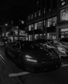 a black and white photo of cars parked on the side of a street at night