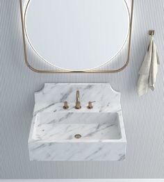 a white sink sitting under a round mirror next to a wall mounted faucet