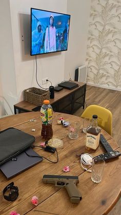 a wooden table topped with lots of items next to a flat screen tv mounted on the wall