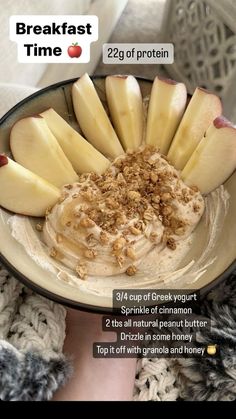 a bowl filled with apples and granola on top of a white plate next to a woman's hand