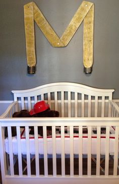 a white crib with a red hat on top and two wooden letters above it