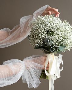 the bride's bouquet is wrapped in tulle and tied with white ribbon,