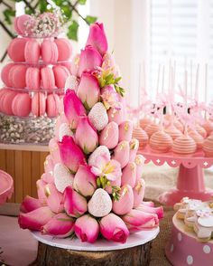 there is a pink cake with flowers on it and other desserts in the background