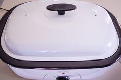 a white and black electric cooker sitting on top of a counter next to a wall