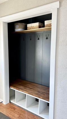 a room with some white shelves and wooden flooring on the wall, along with two bins filled with items