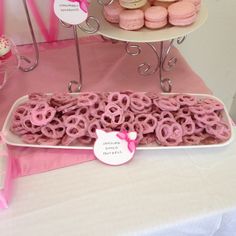 a table topped with pink donuts and cupcakes on top of trays