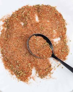 a spoon full of ground spices on top of a white plate